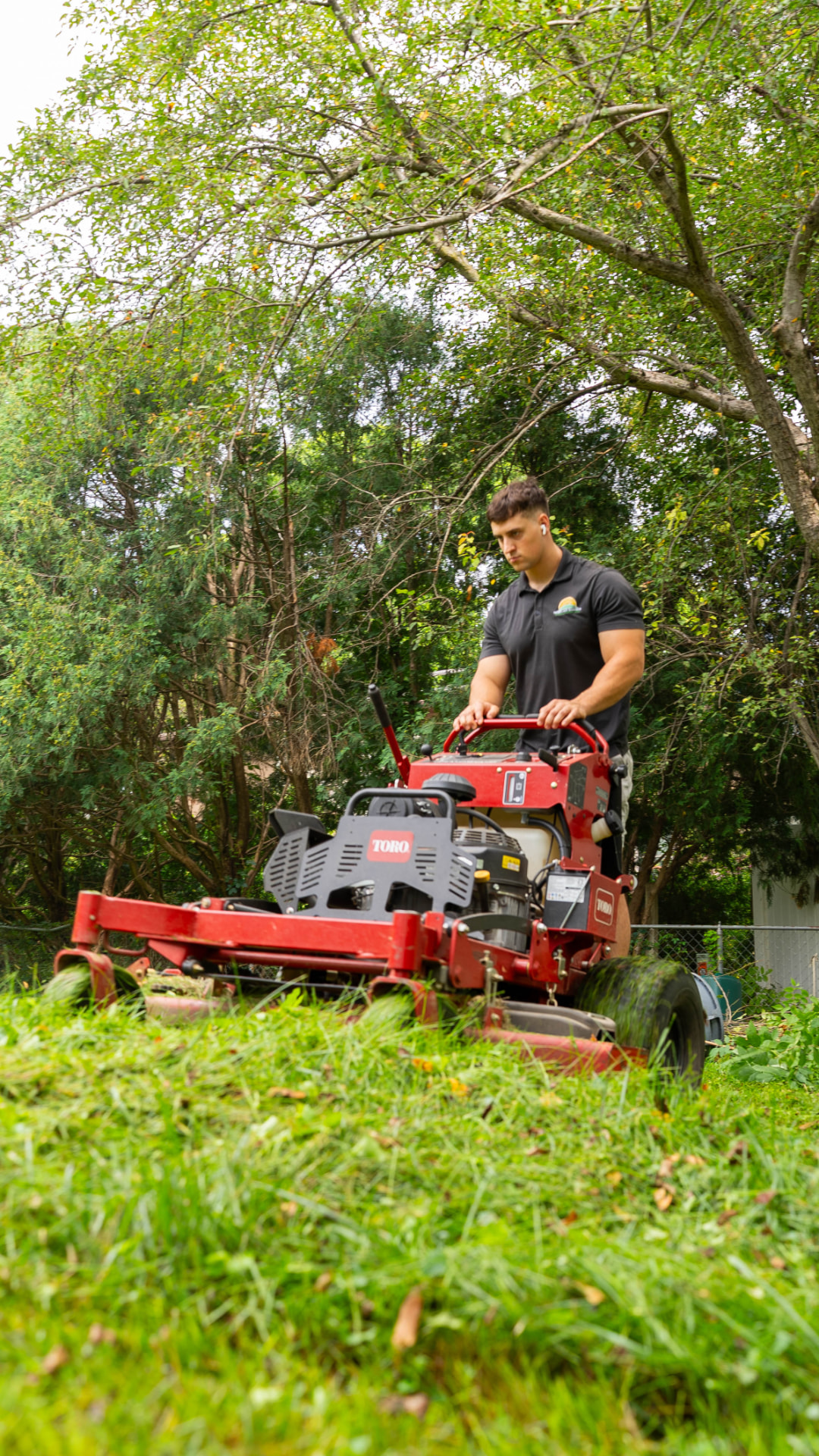 Heartland Grounds crew member mowing down tall overgrown grass with a commercial mower